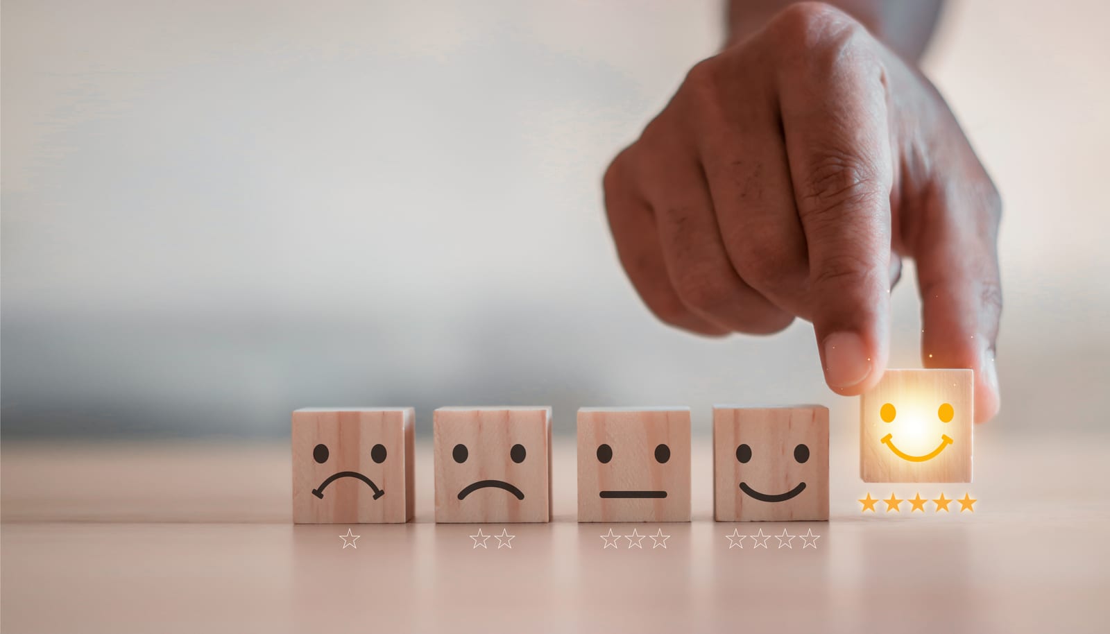 cubos de madeira com caras tristes e felizes representando a satisfacao de uma pessoa